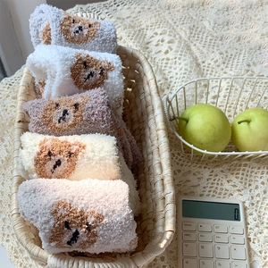 Detail of coral fleece winter socks with bear patterns in a cozy basket setting