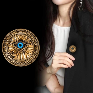 Gold Eye of Horus brooch with blue inlay on a round badge, close-up and model view