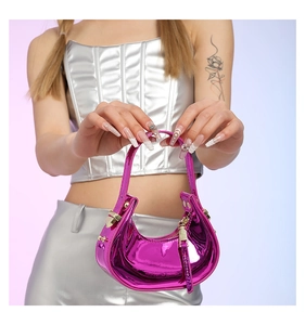 Close-up of pink laser patent leather handbag with gold hardware and tassel detail