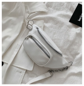 Detail of white PU leather waist bag with silver zippers and metal chain strap accent