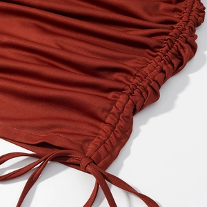 Detail of dark red knitted dress featuring adjustable drawstring and ruched texture