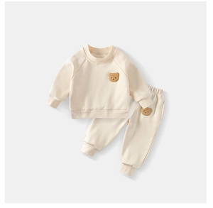 Detail of cream toddler tracksuit featuring cute brown 3D bear embroidery and elastic cuffs