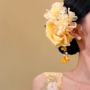 Détail d'une élégante épingle à cheveux fleur en tissu jaune sur le chignon d'un modèle