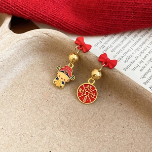 Detail of red bow earrings with lucky God of Wealth charms and golden festive elements