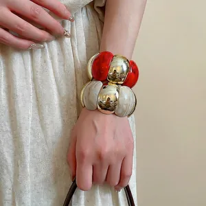 Acrylic marble and gold metal chunky statement bracelets on model's wrist