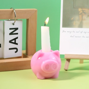 Bougeoir en forme de cochon rose avec une bougie blanche allumée sur un bureau élégant