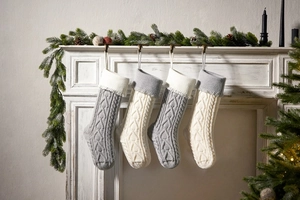 Detailed knit Christmas stockings with heart pattern hanging on a white festive fireplace