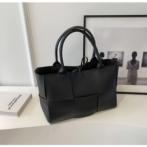 Close-up of premium black woven tote bag with leather texture and large dual handles