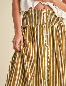 Detail of high waisted striped maxi skirt with elastic smocked waist and button accents