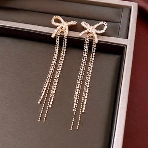 Detail of 18k gold plated bow earrings with sparkling tassel chains on velvet display