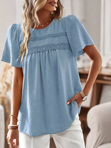Close-up of light blue polka dot blouse featuring delicate white lace trim on the chest