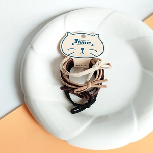 Close-up of earth-toned high elasticity hair ties with knotted bow on white ceramic plate