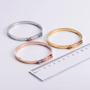 Close-up of three cuff bracelets in gold, silver, and rose gold with colorful crystals