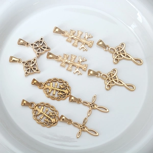 Golden stainless steel Celtic knot and cross pendants displayed on a white ceramic plate