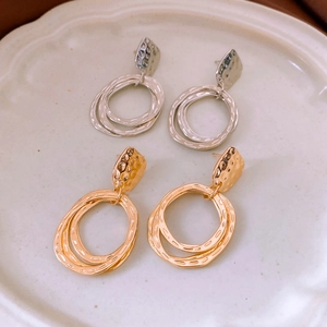 Detail of round pendant earrings with hammered texture and layered hoops in gold and silver