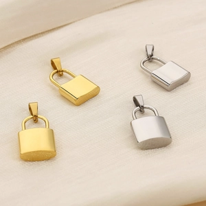 Close-up of gold and silver polished stainless steel lock pendants on beige fabric