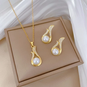 Elegant gold titanium jewelry set with large white pearls and sparkling zircons on silk