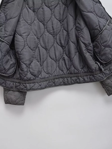 Detailed macro view of gray gourd-quilted lining and smooth zipper closure on jacket