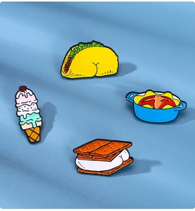 Detail of four colorful enamel pins featuring taco, ice cream, pot, and s'more designs
