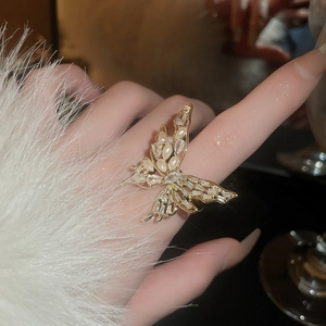 Detail of gold butterfly ring with pearl and cubic zirconia worn on finger
