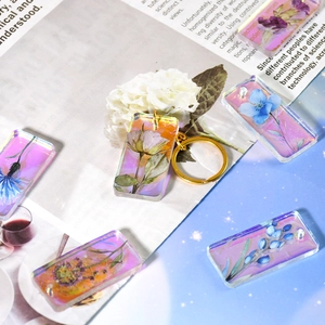 Makro-Detail von Aurora-Acryl-Anhängern mit Trockenblumenmustern und goldenen Ringen