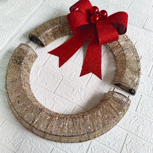 Detail of sectional gold mesh Christmas wreath with LED light and large red glitter bow