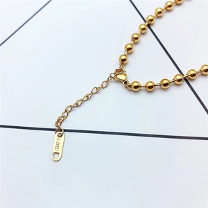 Detail shot of the adjustable gold ball chain showing lobster clasp and S.STEEL tag