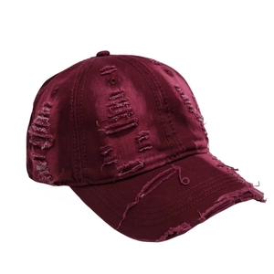 Detail of distressed burgundy satin baseball cap featuring vintage ripped hole textures
