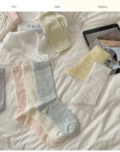 Collection of colorful breathable silk socks in pastel tones on white textured fabric