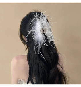 Detailed view of soft white ostrich feathers on a hair claw clip for elegant styling
