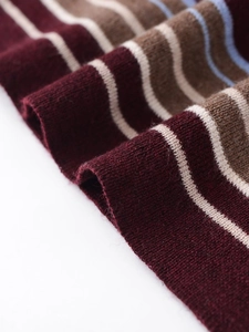 Close-up of the burgundy and coffee striped knit texture on a crew neck long sleeve top
