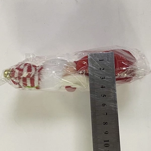 Détail de la mesure de hauteur d'un gnome de Noël en tricot avec une clochette dorée