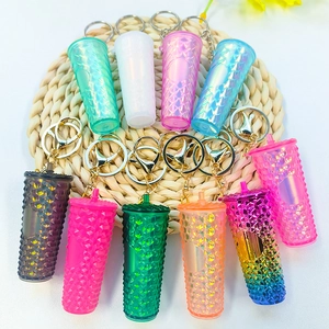 Multiple miniature diamond-textured tumbler keychains in vibrant colors on a rattan mat