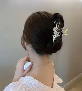 Detailed view of a gold angel hair claw clip with rhinestones worn on a hair bun