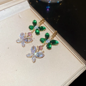 Close-up of golden butterfly earrings with green and white cubic zirconia crystals