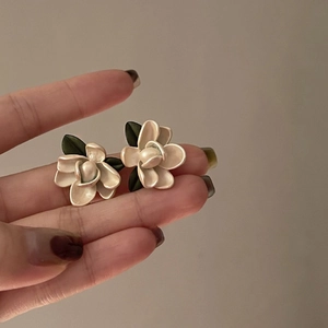 Eleganti orecchini a lobo a fiore di perla bianca con foglia verde tra le dita