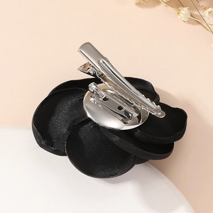 Close-up of the metal clip and safety pin on the back of a black fabric rose brooch