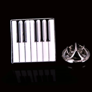 Macro shot of piano keyboard enamel brooch with silver butterfly clutch backing