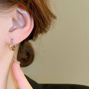 Minimalist silver wavy textured hoop earrings with a polished finish worn on ear