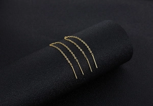 Detailed close-up of golden S925 silver long tassel ear threads on a dark textured display