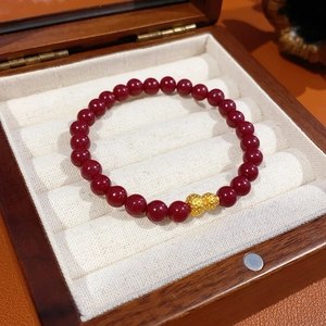 Dettaglio di bracciale in agata rossa con ciondolo a zucca dorata in scatola di legno