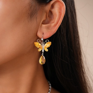 Detailed close-up of butterfly earrings with yellow teardrop crystals on a model