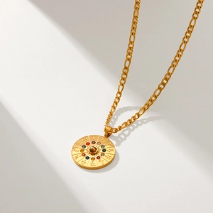 Collana con medaglione zodiacale in acciaio dorato e cristalli colorati su sfondo bianco