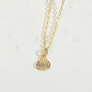 Macro shot of gold shell pendant necklace with sparkling cubic zirconia on white leather