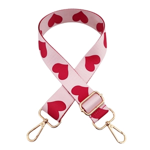 Adjustable pink shoulder strap with red heart pattern and gold metal hooks