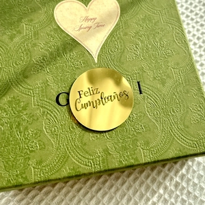 Detail of dark green embossed gift box with Feliz Cumpleaños gold sticker