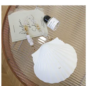 Detail of white shell evening bag with pearl accent and acrylic chain on glass