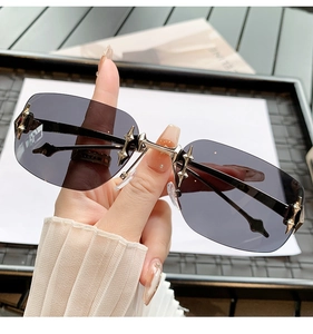 Close-up of rimless Y2K sunglasses with gold star hardware and dark gradient lenses