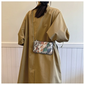 Detail of snake skin pattern envelope bag with metal bead trim and chain strap