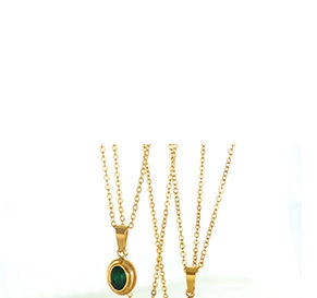Detail of a thin golden necklace featuring an oval dark green gemstone pendant
